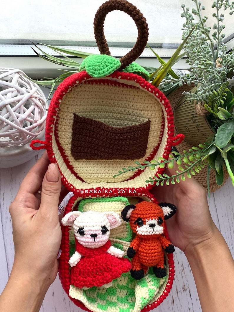 Display of the open apple-shaped bag with cute crochet foxes inside. A thoughtful DIY crochet project to create with love.