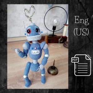 May include: Crochet amigurumi robot pattern in PDF format. The robot is blue and gray with a heart on its chest and a heart-shaped antenna. The pattern is available in English (US).