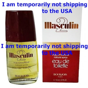 May include: A bottle of "Masculin" eau de toilette with a dark burgundy cap and a matching box. The bottle is yellow with a clear label. The box is white with red accents. The text "Masculin" is visible on both the bottle and the box.