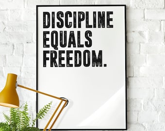 Puede incluir: Un póster motivacional en blanco y negro con el texto "DISCIPLINE EQUALS FREEDOM." El póster está enmarcado en un marco negro y está colgado en una pared de ladrillo blanco.