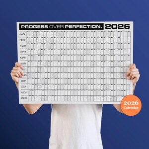 Könnte beinhalten: Ein weißer Kalender für 2026 mit dem Text "PROGESS OVER PERFECTION." oben. Das Kalendarium ist in Monate und Tage unterteilt. Ein orangefarbener Kreis mit dem Text "2026 Calendar" befindet sich unten rechts.