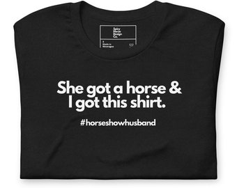 May include: Black t-shirt with white text that reads "She got a horse & I got this shirt. #horseshowhusband"