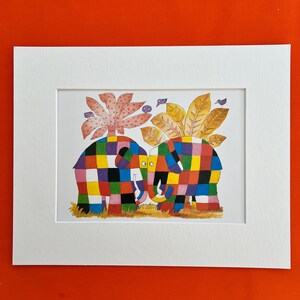 May include: A framed watercolour print depicting two elephants with vibrant, patchwork-style patterns. They face each other, set against a backdrop of stylized pink and gold foliage. The artwork is presented within a white mount.