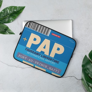 May include: Blue laptop sleeve with a luggage tag design. The tag says "PAP Toussaint Louverture International Airport Port-au-Prince, Haiti".