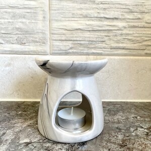 May include: White ceramic oil burner with a marble design and a small white tea light candle in the centre.