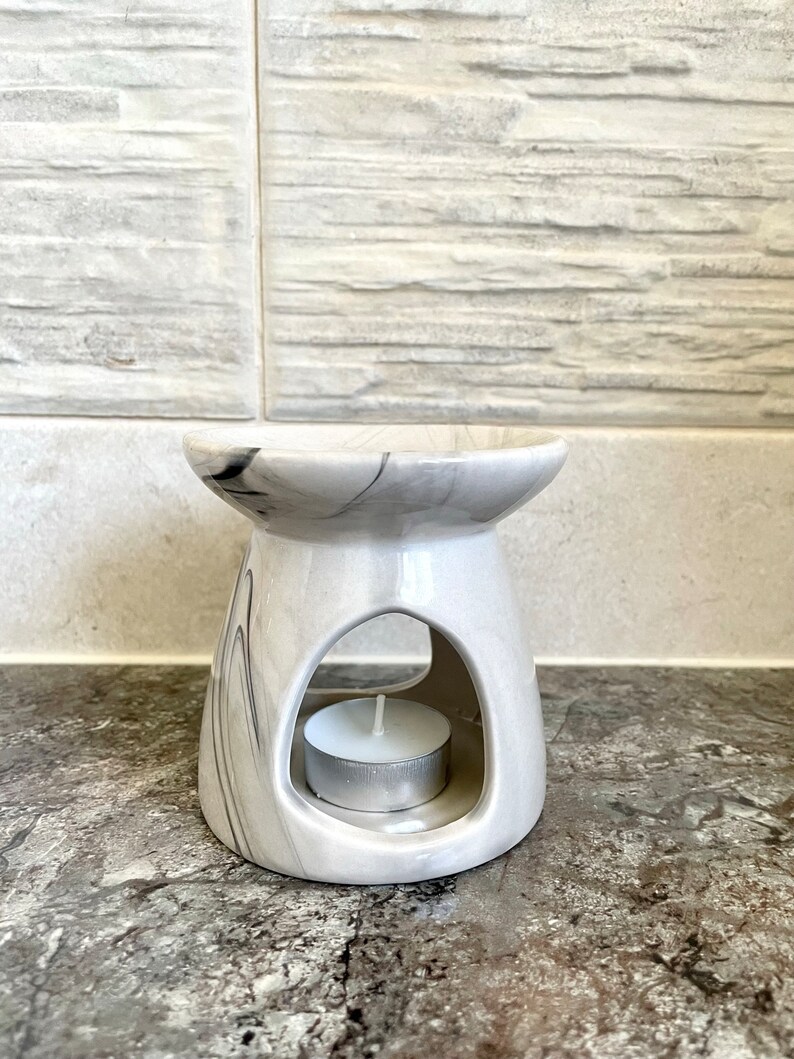 May include: White ceramic oil burner with a marble design and a small white tea light candle in the centre.
