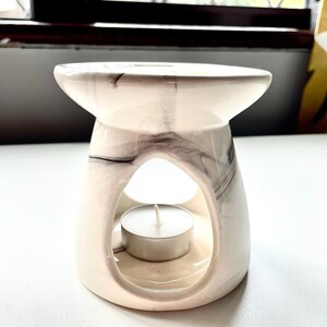 May include: White ceramic wax melt burner with a grey marbled design. The burner has a round opening in the centre to hold a tea light candle.