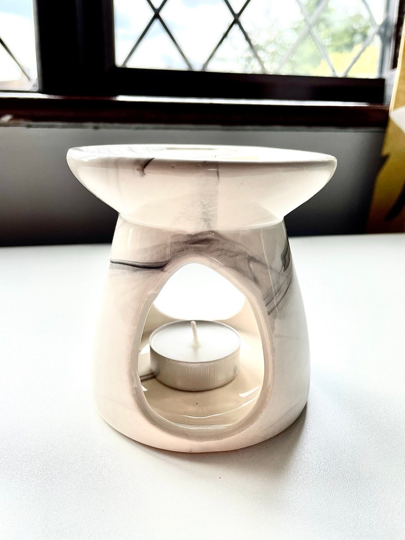 May include: White ceramic wax melt burner with a grey marbled design. The burner has a round opening in the centre to hold a tea light candle.