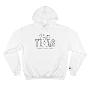 Pode incluir: Hoodie branco Champion com uma estampa gráfica preta que diz "Houston TEXAS" e "Everything's bigger in Texas".
