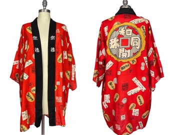 May include: A red silk kimono with black trim and a large gold and white circle on the back with Japanese characters. The kimono is covered in a pattern of smaller gold and white circles with Japanese characters.