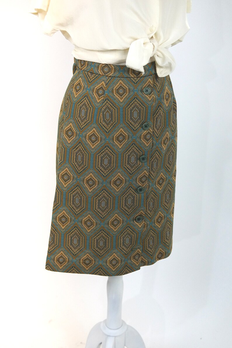 May include: A brown and blue geometric patterned skirt with a button closure. The skirt is knee-length and has a straight silhouette.