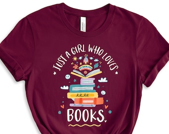Puede incluir: Camiseta color burdeos con un gráfico de una pila de libros con el texto "Just a girl who loves books."