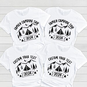 Pu&ograve; includere: Quattro magliette bianche con disegni grafici neri. Due magliette presentano il testo "Family Camping Trip" con una scena di montagna, un fal&ograve;, una tenda e stelle. Le altre due magliette presentano il testo "Custom Your Text" con la stessa scena di montagna, fal&ograve;, tenda e stelle.