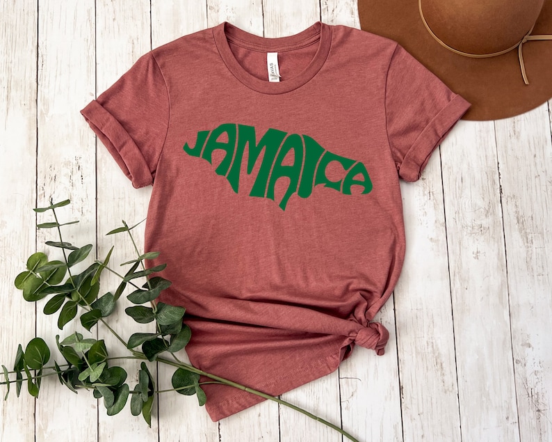 May include: A maroon t-shirt with a green outline of the island of Jamaica and the word "Jamaica" written in a stylized font.