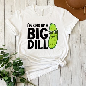 Peut inclure: T-shirt blanc avec un graphique noir d'un cornichon portant des lunettes de soleil et le texte "Je suis un peu un gros cornichon".