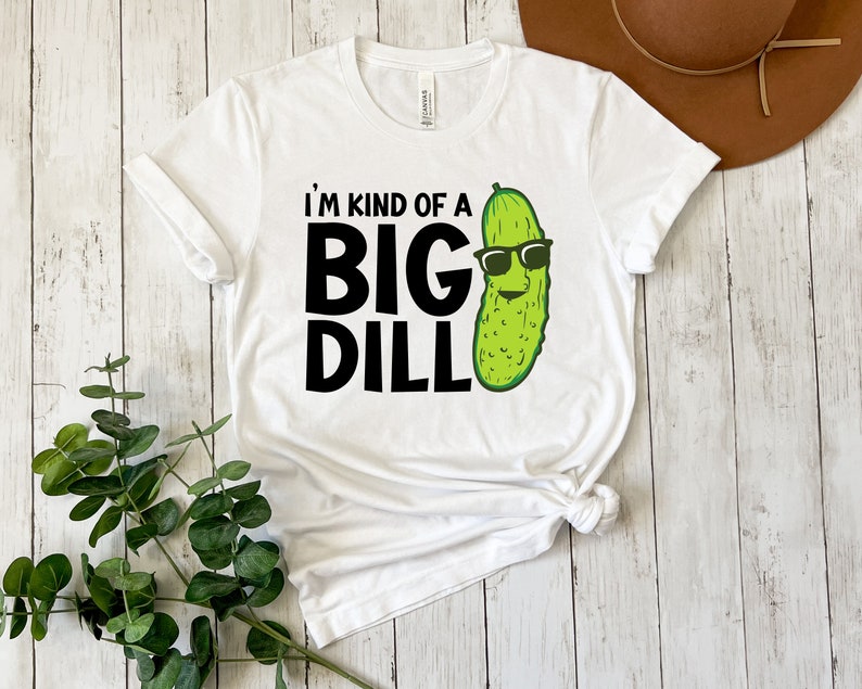 Peut inclure: T-shirt blanc avec un graphique noir d'un cornichon portant des lunettes de soleil et le texte "Je suis un peu un gros cornichon".