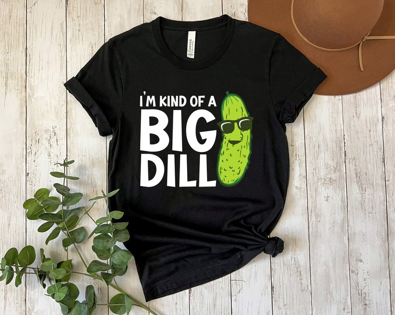 Peut inclure: T-shirt noir avec du texte blanc qui dit "I'm kind of a big dill" et un cornichon vert portant des lunettes de soleil.