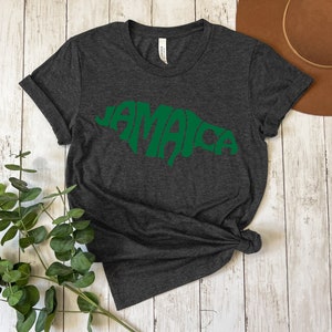 May include: Dark gray t-shirt with a green outline of the island of Jamaica, with the word "Jamaica" spelled out within the outline.
