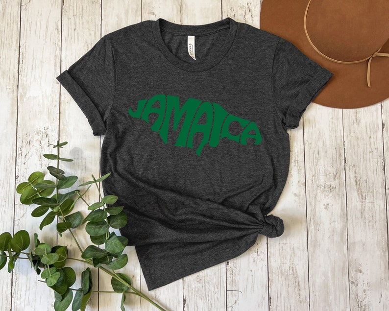 May include: Dark gray t-shirt with a green outline of the island of Jamaica, with the word "Jamaica" spelled out within the outline.