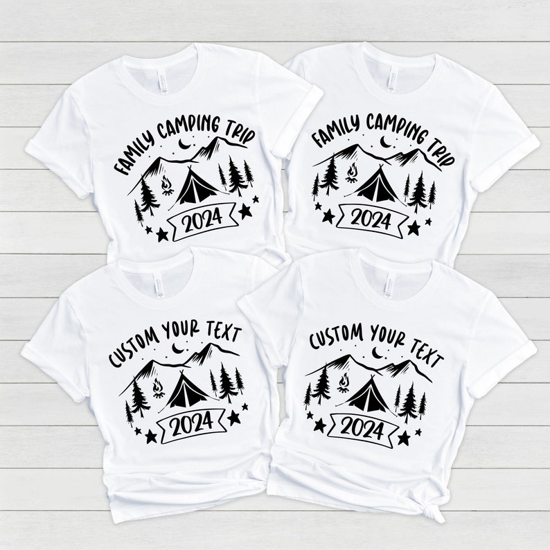 Pu&ograve; includere: Quattro magliette bianche con disegni grafici neri. Due magliette presentano il testo "Family Camping Trip" con una scena di montagna, un fal&ograve;, una tenda e stelle. Le altre due magliette presentano il testo "Custom Your Text" con la stessa scena di montagna, fal&ograve;, tenda e stelle.