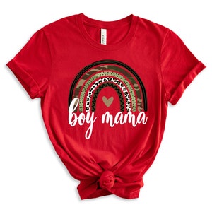 K&ouml;nnte beinhalten: Rotes T-Shirt mit einem Regenbogen-Design mit Tarnmuster, Leopardenmuster und einem Herzen. Der Text "boy mama" ist unter dem Regenbogen gedruckt.