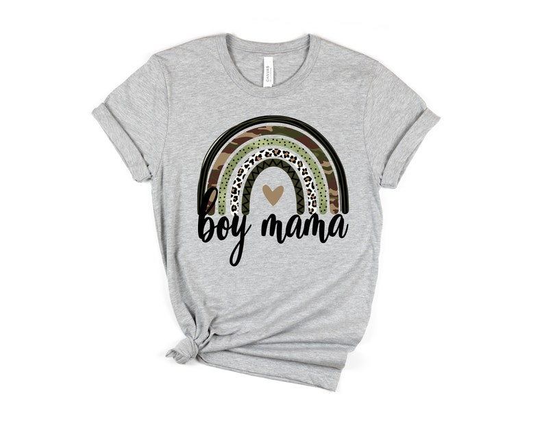 K&ouml;nnte beinhalten: Ein graues T-Shirt mit einem Regenbogen-Design mit Tarnmuster, Leopardenmuster und schwarz-wei&szlig;en Mustern. Der Regenbogen hat ein kleines Herz in der Mitte. Der Text "boy mama" ist unter dem Regenbogen gedruckt.