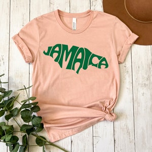 May include: A light pink t-shirt with a green graphic of the word "Jamaica" in a retro font.