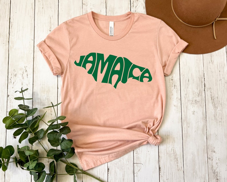 May include: A light pink t-shirt with a green graphic of the word "Jamaica" in a retro font.