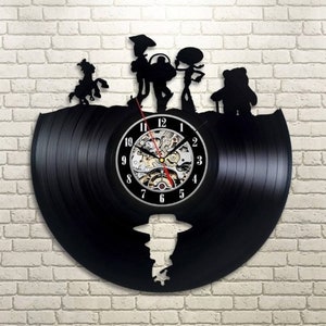 May include: A black vinyl record clock featuring a silhouette of Woody, Buzz Lightyear, Jessie, and Bullseye from the Toy Story movie franchise. The clock face is a white circle with black numbers and hands.