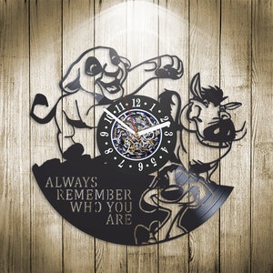Puede incluir: Reloj de vinilo negro con Simba y Pumbaa de El Rey León de Disney. La esfera del reloj es un círculo más pequeño con números romanos y una cita que dice "Recuerda siempre quién eres".