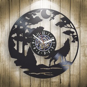 Könnte beinhalten: Schwarze Schallplattenuhr mit einem Wolf, der in einer Waldszene zum Mond heult. Das Zifferblatt der Uhr hat schwarze römische Ziffern und einen goldenen Zeiger.