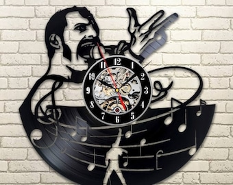 Könnte beinhalten: Eine schwarze Schallplattenuhr mit der Silhouette eines Sängers mit Mikrofon. Das Zifferblatt der Uhr ist ein silberfarbenes Analoguhr mit schwarzen Zahlen und Zeigern. Die Schallplatte ist mit Noten verziert.