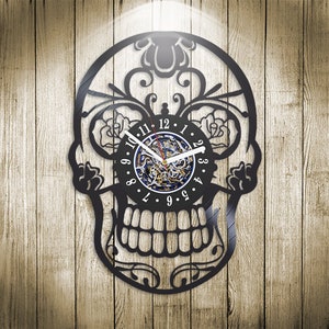 Può includere: Orologio in vinile nero a forma di teschio di zucchero con dettagli floreali. Il quadrante dell'orologio ha numeri romani e un design a chiave scheletrica.