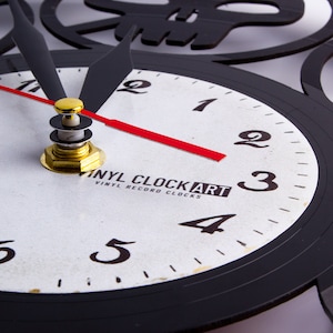 May include: A black vinyl record clock with white numbers and a red second hand. The clock face has the text "Vinyl ClockArt Vinyl Record Clocks".