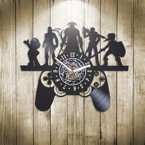 May include: Black vinyl record clock featuring a video game controller design with a clock face in the centre. The clock face has a black and white design with a blue centre. The controller has a black and white design with a black and white design. The clock is surrounded by five figures, including a warrior, a mage, a rogue, a ranger, and a cleric. The clock is set against a woodgrain background.