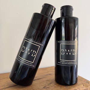May include: Two black glass bottles with black labels and white text. The labels read "Premium Fragranced Diffuser Oil" and include the website address "www.bellaswaxbarn.co.uk".