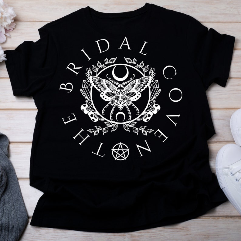May include: Black t-shirt with a white graphic design featuring a moth, crescent moons, and the text "The Bridal Coven".