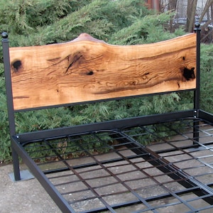 Peut inclure: Un cadre de lit en métal noir avec une tête de lit en bois. La tête de lit est faite d'une seule pièce de bois avec un bord naturel et une finition rustique.