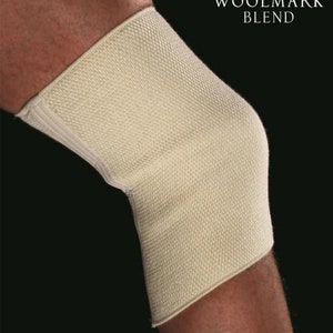 May include: A beige knee brace made of a woven material, worn on a leg. The brace covers the knee and extends above and below it. The Woolmark Blend logo is visible in the upper right corner.