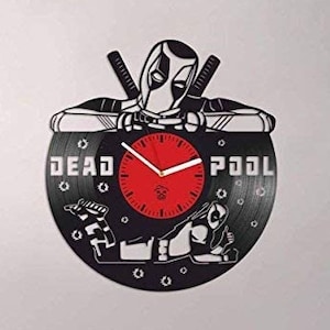 Könnte beinhalten: Eine schwarze Schallplattenuhr mit einer Silhouette von Deadpool und dem Text "DEAD POOL" auf der Schallplatte. Die Uhr hat ein rotes Zifferblatt mit weißen Zeigern und schwarzen Zahlen.