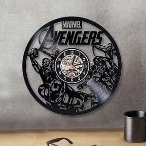 May include: Black vinyl record clock featuring the Marvel Avengers logo and characters. The clock has a black background with a silver clock face and black hands.