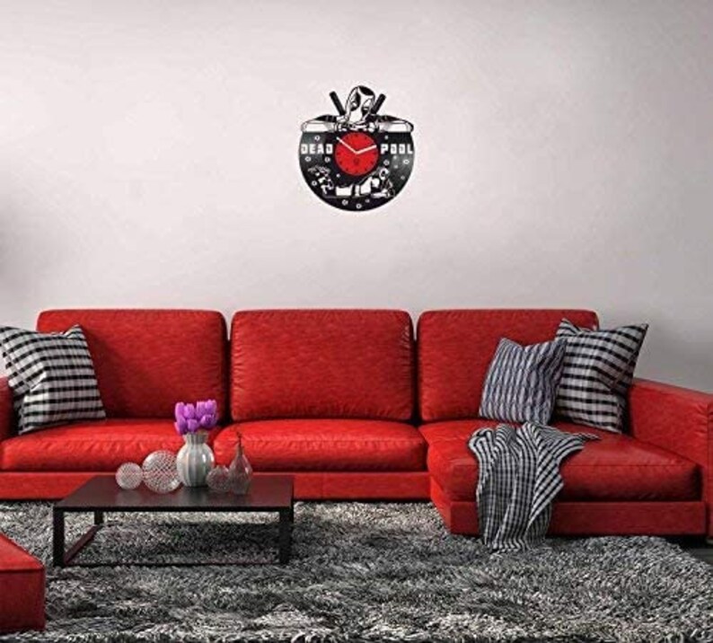 May include: A black vinyl record clock featuring a silhouette of Deadpool with the words "DEAD POOL" printed on the record. The clock hands are red and the background is black.