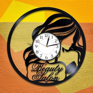 May include: Black vinyl record clock with a silhouette of a woman's face and hair, with a white clock face and black hands. The clock face has the numbers 1-12 and the text "Beauty Salon" is printed below the clock face.