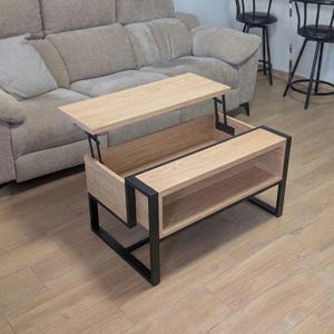 Tavolino da caffè moderno in stile industriale con piano sollevabile, struttura in acciaio e rovere massello con vano contenitore nascosto, realizzato a mano in Spagna.