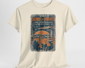 May include: Cream-colored t-shirt featuring a vintage-style graphic. The graphic reads "VISIT CAROUSEL of PROGRESS" with text below indicating a Walt Disney presentation at the 1964-65 N.Y. World's Fair. The design includes a retro illustration.