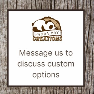 Pode incluir: Um quadrado branco com uma borda marrom e um logotipo de panda com o texto "Panda Bay Creations". Abaixo do logotipo, o texto diz "Entre em contato conosco para discutir op&ccedil;&otilde;es personalizadas". O fundo &eacute; uma textura de madeira.