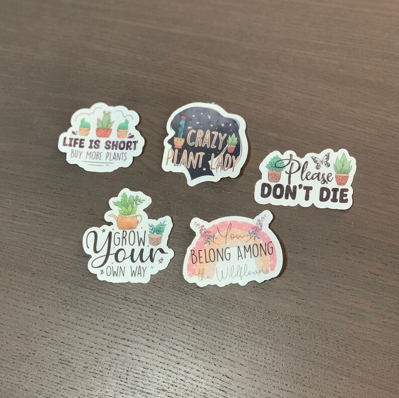 May include: Five colorful stickers with plant illustrations and text. The stickers say "Life is short, buy more plants", "Crazy plant lady", "Please don't die", "Grow your own way", and "You belong among the wildflowers".