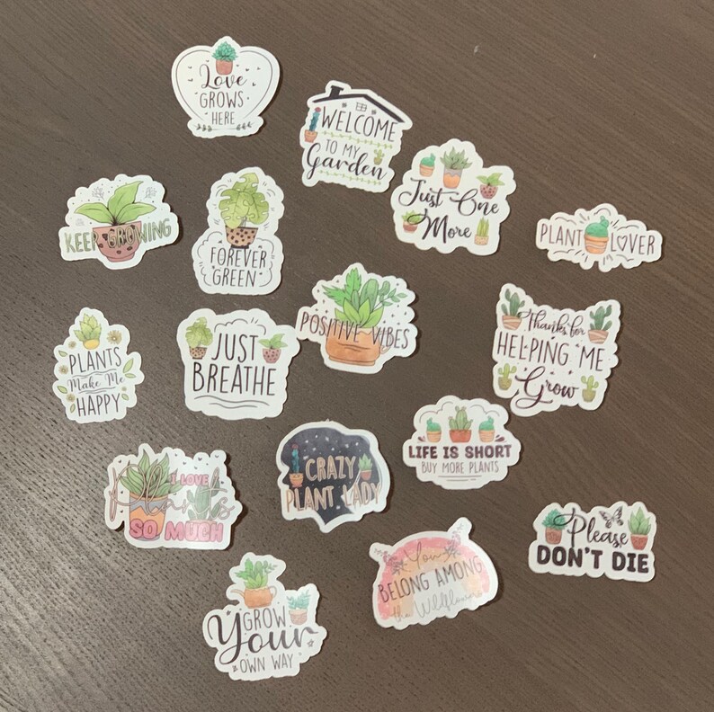 May include: A collection of 15 colorful plant-themed stickers with various sayings, including "Keep Growing", "Forever Green", "Just Breathe", "Positive Vibes", "Plants Make Me Happy", "Crazy Plant Lady", "Life is Short Buy More Plants", "Welcome to My Garden", "Just One More", "Plant Lover", "Thanks for Helping Me Grow", "Please Don't Die", "I Love So Much", "Grow Your Own Way", and "Belong Among the Wildflowers".