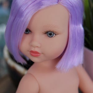 May include: A doll with a fair complexion and blue eyes, wearing a lavender wig. The doll's lips are painted a rosy pink. The doll is a close-up shot, with the focus on the face and upper body.