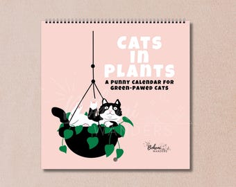 Könnte beinhalten: Ein Spiral-Kalender mit rosa Hintergrund zeigt eine schwarz-weiße Katze in einer Hängepflanze. Der Text "CATS IN PLANTS" und "A PUNNY CALENDAR FOR GREEN-PAWED CATS" sind zu sehen. Der Kalender ist von "Bohemi Wanders".